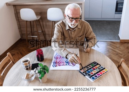 Cropped shot of a mature man painting while sitting on the kitchen table at home. Royalty-Free Stock Photo #2255236777