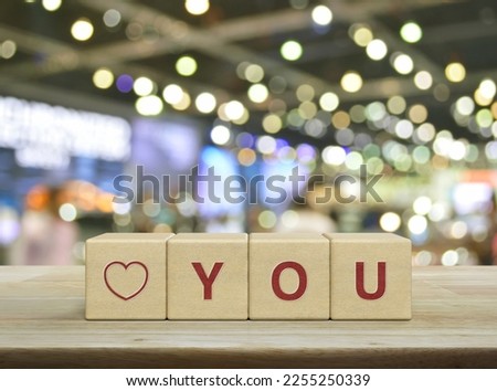 Love you letter on wood block cubes on wooden table over blur light and shadow of shopping mall, Valentines day concept