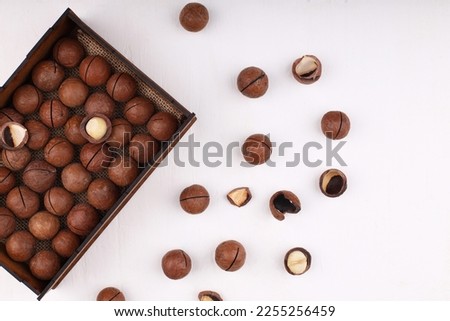 Close-up of macadamia nuts on a white stone, slate or concrete background, the concept of superfoods and healthy nutrition, a picture from above or with a view from above in a vintage color tone