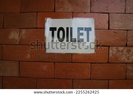 Toilet sign on brick wall