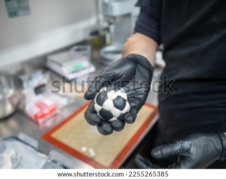 pastry chef designer making a football soccer ball as a frosted cake topper photo