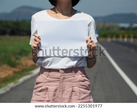 woman holding white paper On the road. Space for advertising. copy space