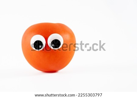 large sun ripened tomato with cartoon rolling googly eyes isolated on white background Royalty-Free Stock Photo #2255303797