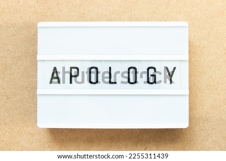 Lightbox with word apology on wood background