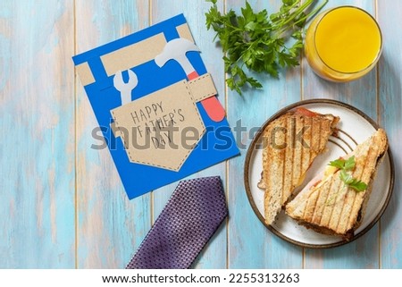 Celebrating Father's Day. Breakfast. Father’s Day card and home DIY sandwich with bacon on wooden table. View from above. Copy space.