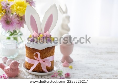 traditional easter cake kulich decorated with funny bunny  ears cookies, sprinkles end candy eggs. Happy Easter and spring holiday concept, copy space Royalty-Free Stock Photo #2255326217