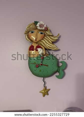 An analogue clock in the shape of a mermaid.