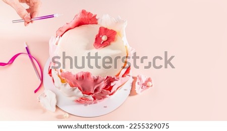 baker adds candle to festive cake, selective focus, copy space. Close shot of human hand With pink candle on foreground. woman piping decoration on cake,banner with food.