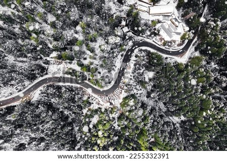 Aerial view of beautiful road between snow covered trees