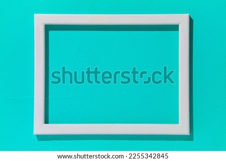 Blank white wooden frame on turquoise background. Mockup design