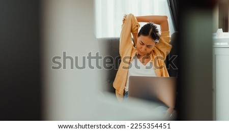 Young asia female girl or university student sit on sofa chair with computer laptop feel pain, hurt shoulder from hard work overtime in living room at home. Office syndrome, Work life balance concept. Royalty-Free Stock Photo #2255354451