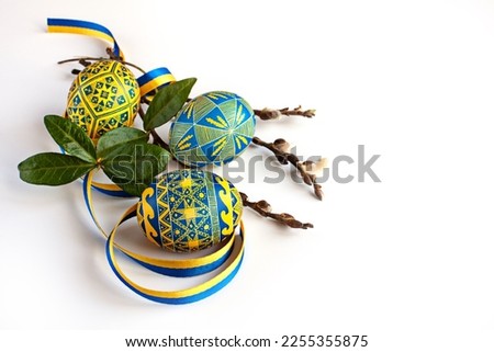 traditional Ukrainian Easter eggs in national colors, twigs of willow and periwinkle and a yellow-blue ribbon on a white background Royalty-Free Stock Photo #2255355875