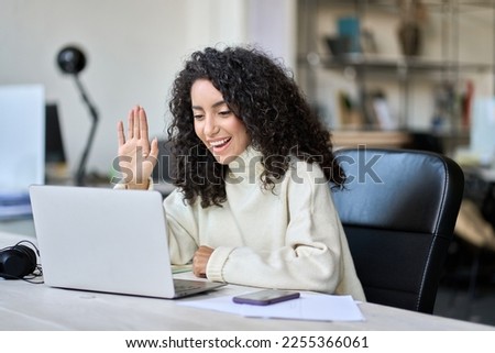 Happy young latin business woman employee, hr manager having remote videocall work hybrid meeting or job interview waving hand looking at laptop during virtual video conference call in office. Royalty-Free Stock Photo #2255366061
