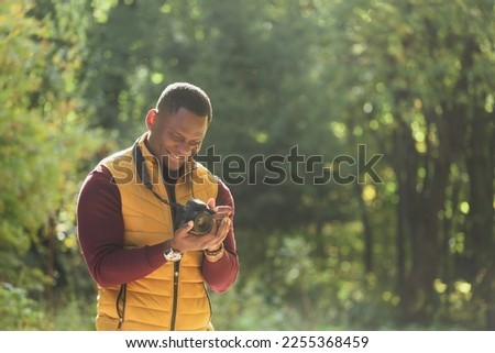 Close-up african american guy photographer taking picture with photo camera on city green park copy space and place for text - leisure activity, diversity and hobby concept