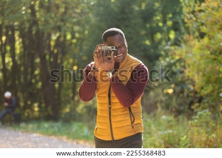 African american guy photographer taking picture with vintage camera on city green park copy space - leisure activity, diversity and hobby concept