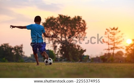 An action sport of a group of kids playing soccer football for exercise in community rural area under the sunset. picture with copy space for digital detox activity for children.
