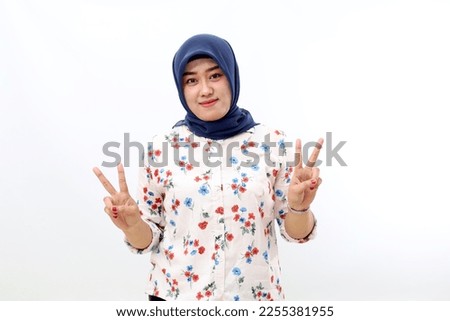 Cheerful asian muslim woman standing while showing victory hand gesture, Isolated on white