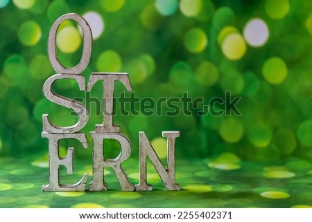 Wooden letters on a green background, festive decoration for banner, poster, flyer, card, card, cover, brochure with the inscription Easter in German, closeup