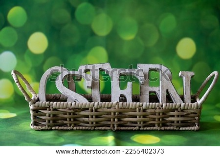 Wooden letters on a green background, festive decoration for banner, poster, flyer, card, card, cover, brochure with the inscription Easter in German, closeup