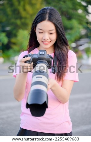 beautiful happy asian woman photographer holding professional camera with telephoto lens