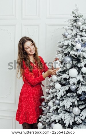 woman decorates a Christmas tree with white balls new year white christmas tree