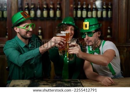 Three friends sharing beers in a bar for St. Patrick's Day.