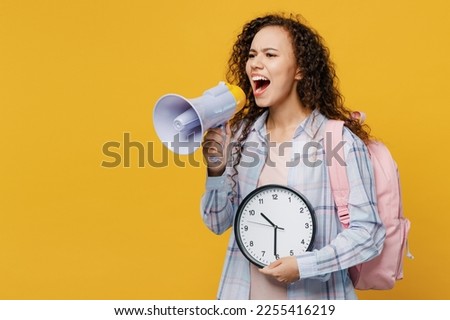 Young black teen girl student she wearing casual clothes backpack bag hold clock scream in megaphone discounts sale Hurry up isolated on plain yellow background. High school university college concept Royalty-Free Stock Photo #2255416219