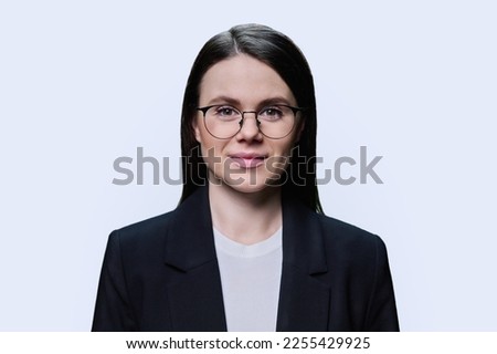 Headshot portrait of young woman in glasses looking at camera on white background
