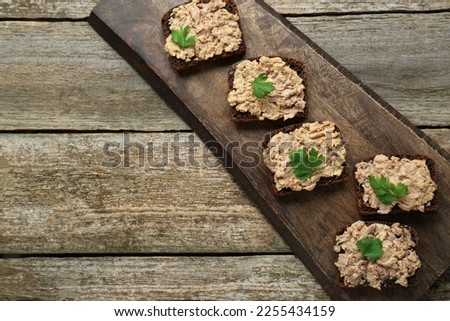 Tasty sandwiches with cod liver and parsley on wooden table, top view. Space for text