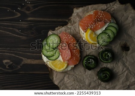 a healthy hearty breakfast of round toasts with cheese, lightly salted red fish, salmon, fresh cucumbers sprinkled with white sesame seeds and lemon slices. for screensavers labels flyers advertising 