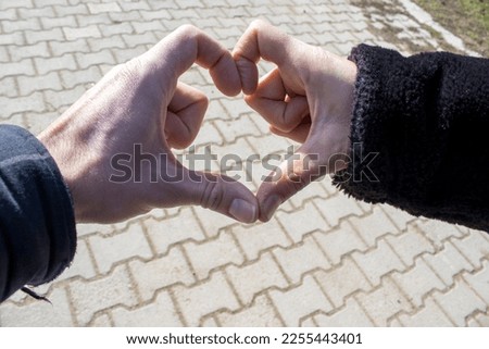Happy couple making heart shape with hands together.