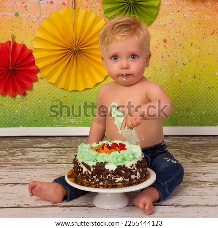 Colorful images shot during the first birthday party of a little blonde boy smashing his birthday cake with wooden spoons