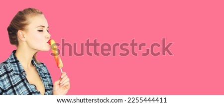 Portrait of beautiful young woman enjoying sweet ice cream or lollipop on pink background, blank copy space for advertising text