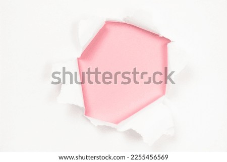 Torn white paper with hole on pink paper background, copy space