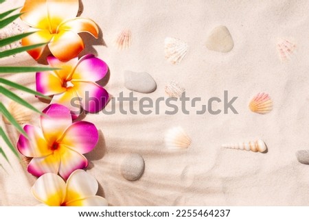 Plumeria flowers on white sand. Tropical beach background