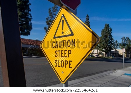 Yellow sign with graphic and exclamation point indicating a steep slope