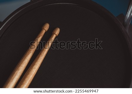 Close up picture of brown drum sticks on the black drum. Detail of snare drum drum sticks. Percussion musical instruments. Soft focus. Music concept and beats waiting to happen.