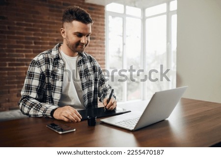 A professional photographer or graphic designer is sitting at his office desk. Man in office with digital graphics tablet and pen for drawing.