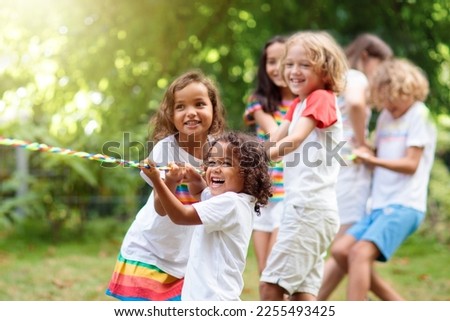 Kids play tug of war in sunny park. Summer outdoor fun activity. Group of mixed race children pull rope in school sports day. Healthy outdoor game for little boy and girl. Royalty-Free Stock Photo #2255493425