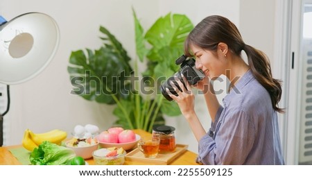 Female Asian photographer taking pictures of healthy food with satisfaction
