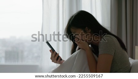 sad asian woman look smart phone feeling depressed of receiving internet bullying message or email with bad news sit on bed in bedroom at home Royalty-Free Stock Photo #2255509167