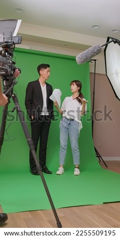 Asian film crew working together communicating infront of green screen