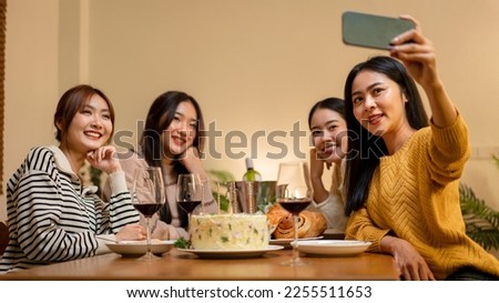 Young people sitting on the couch to smiling with enjoying and using smartphone to selfie together while dinner and celebrating in new year party at home.