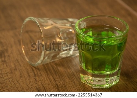 close up of shot glasses lined up on wooden bar background filled with green spirit cocktail and drunk at celebration for St Patrick's day 2023. Irish holiday popular drinking event when people party