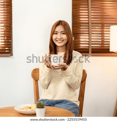 Young woman lesbian looking camera to smiling and enjoying with drinking hot chocolate while spending time to relaxation in living room at home.