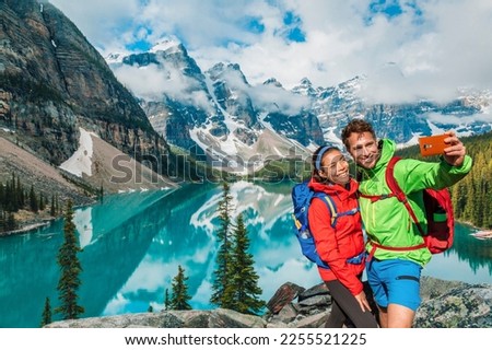 Moraine lake Couple tourists taking selfie picture on Canada travel hike using phone. Young hikers happy using phone on Banff holiday