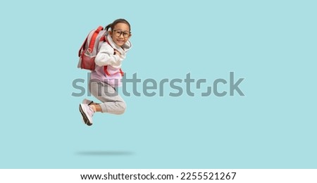 School girl, Happy Asian student school kid jumping for joy with backpack, Full body portrait isolated on pastel plain light blue background with clipping path for design work Royalty-Free Stock Photo #2255521267