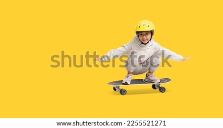 Happy asian little girl playing skateboard wearing a helmet, Full body portrait isolate on yellow background with clipping path for design work