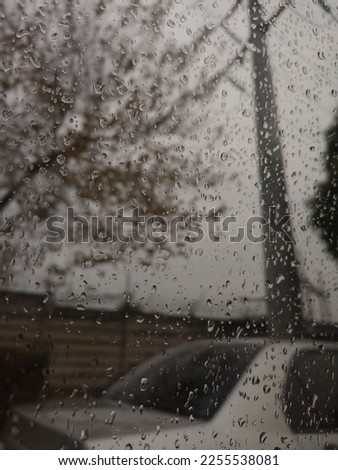 Photograph of a rainy day. The rainy day is captured through the window of a car. 
