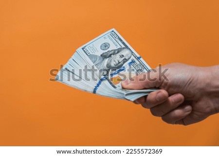 Hand with money on orange background. American dollars. Money or Business concept. 